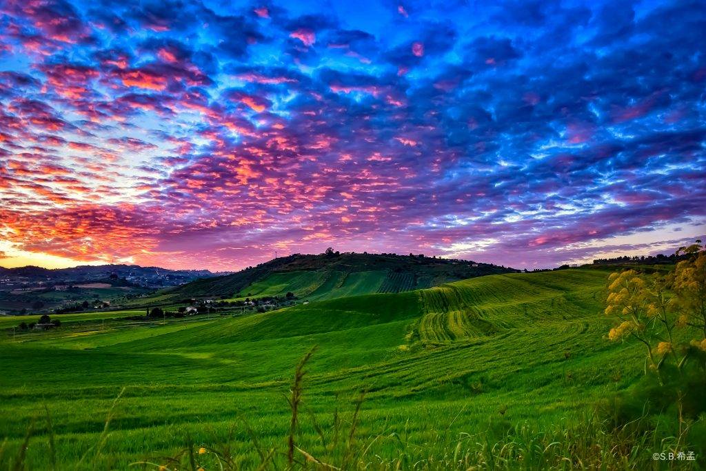 Mackerel sky at sunset on green hills